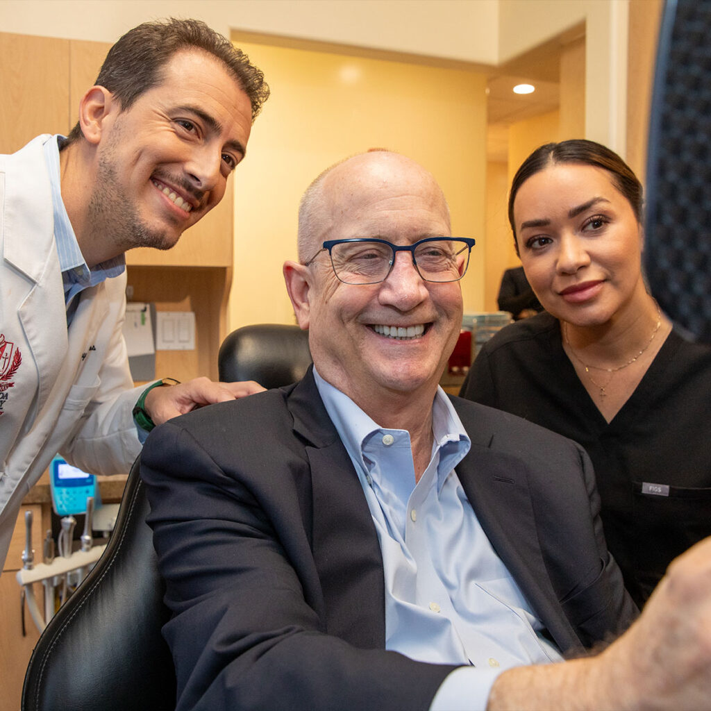 patient smiling brightly after their dental procedure with doctor and staff member