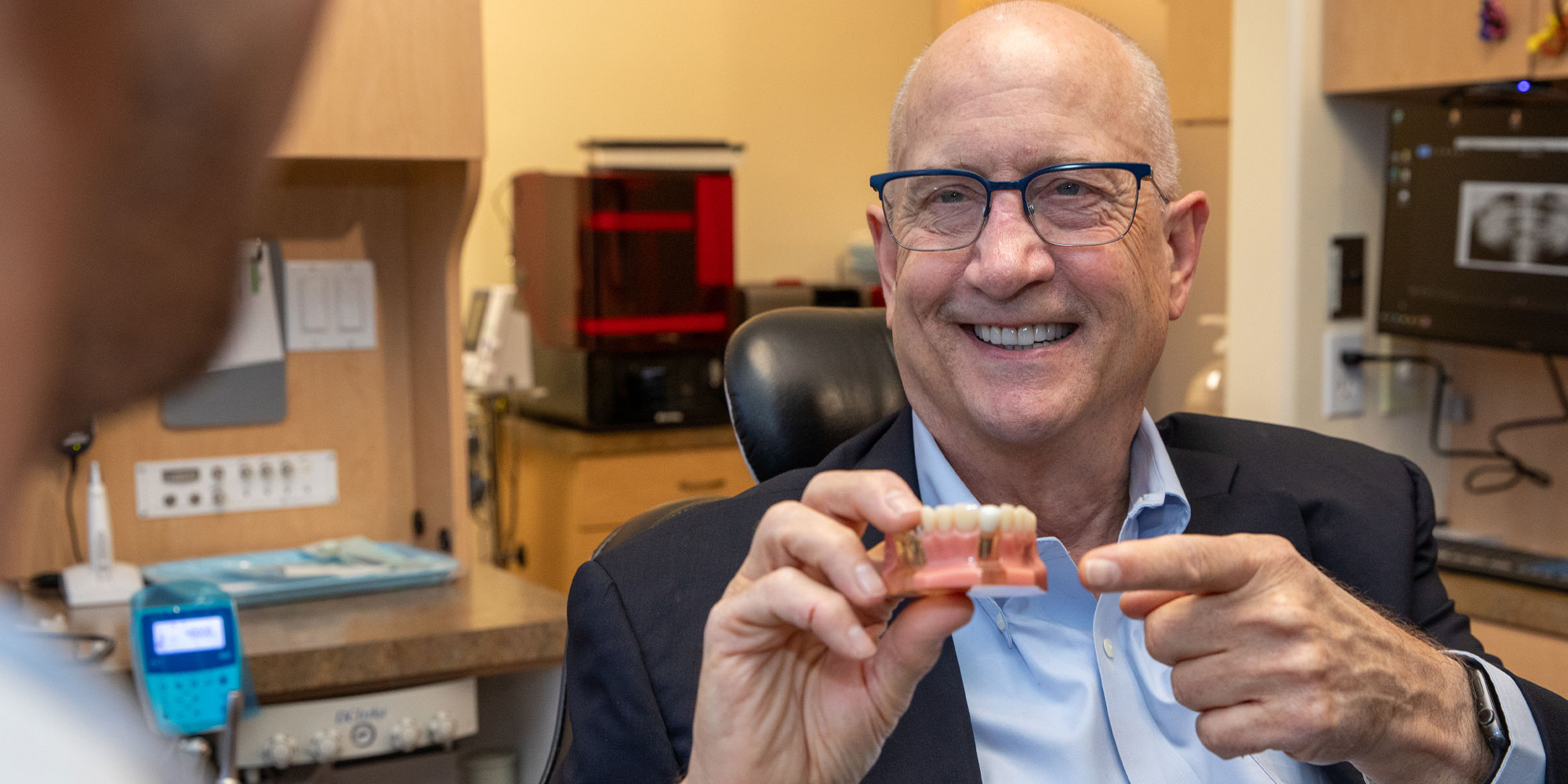 patient holding a full arch model within the dental center