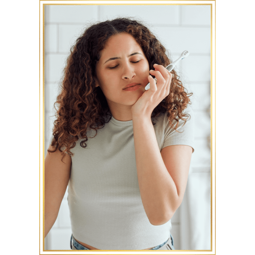 female having mouth pain while trying to brush their teeth